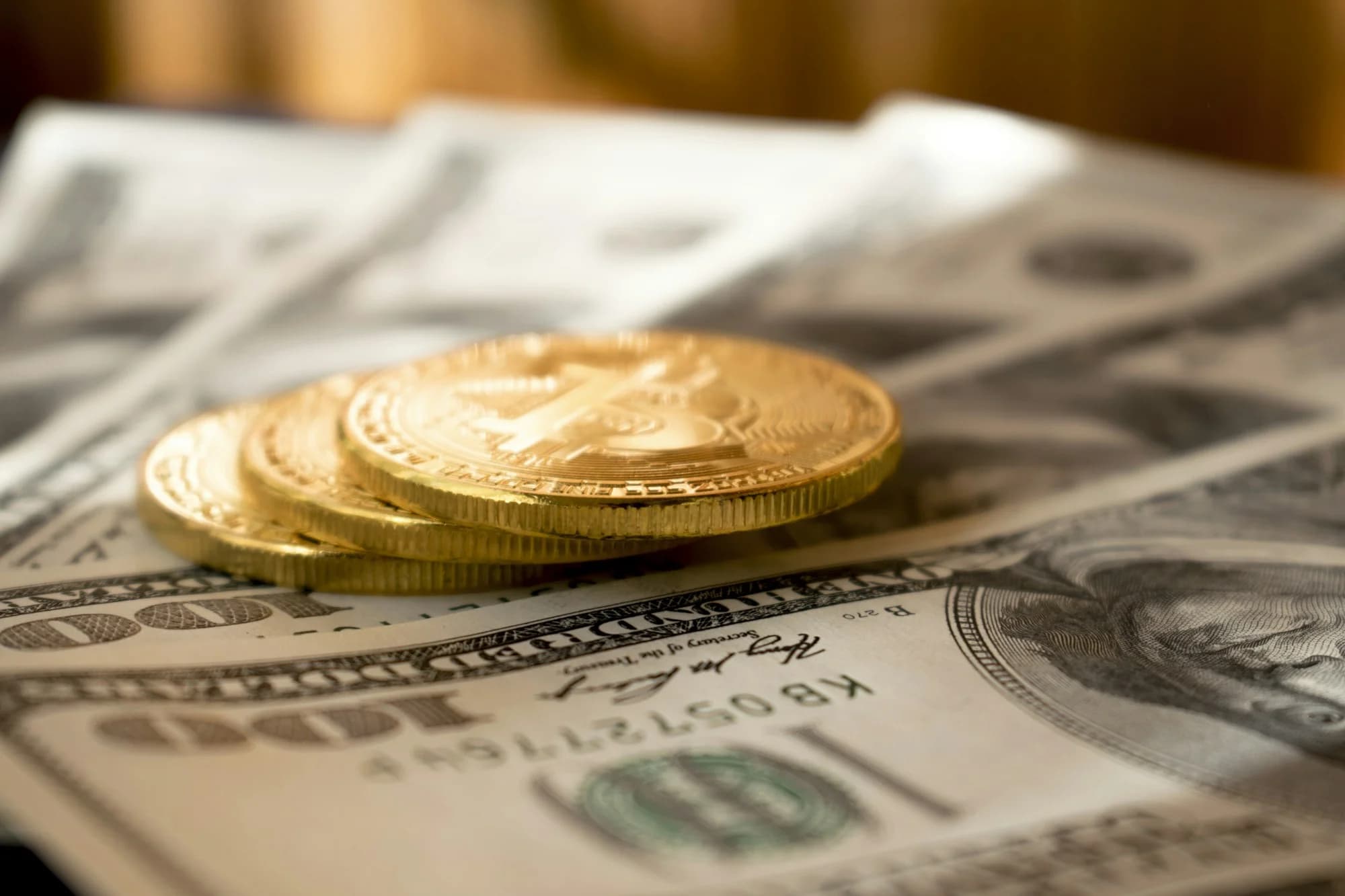 Gold coins on US dollar banknotes (Dmytro Demidko, Unsplash)