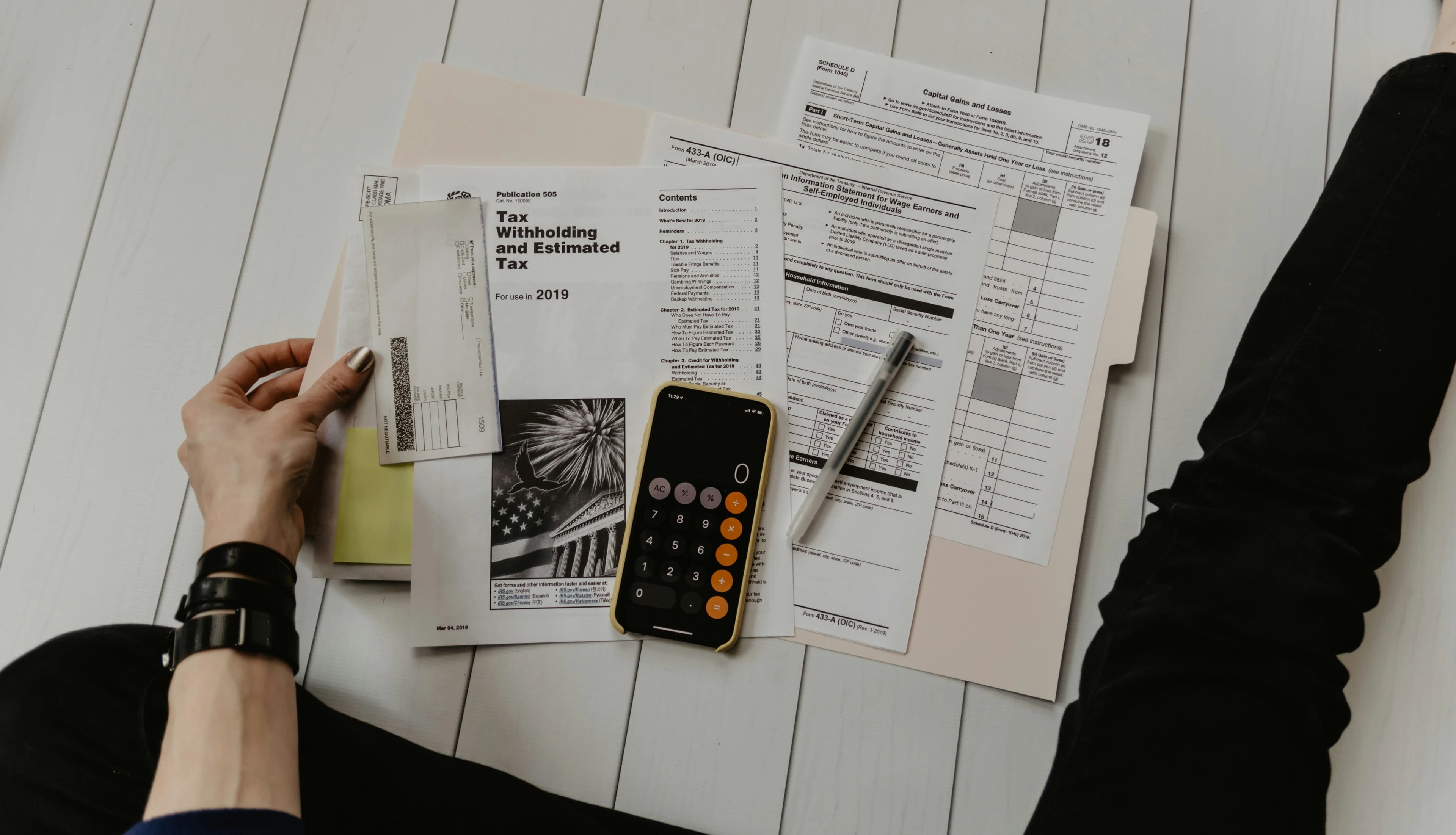 Person holding paper near pen and calculator