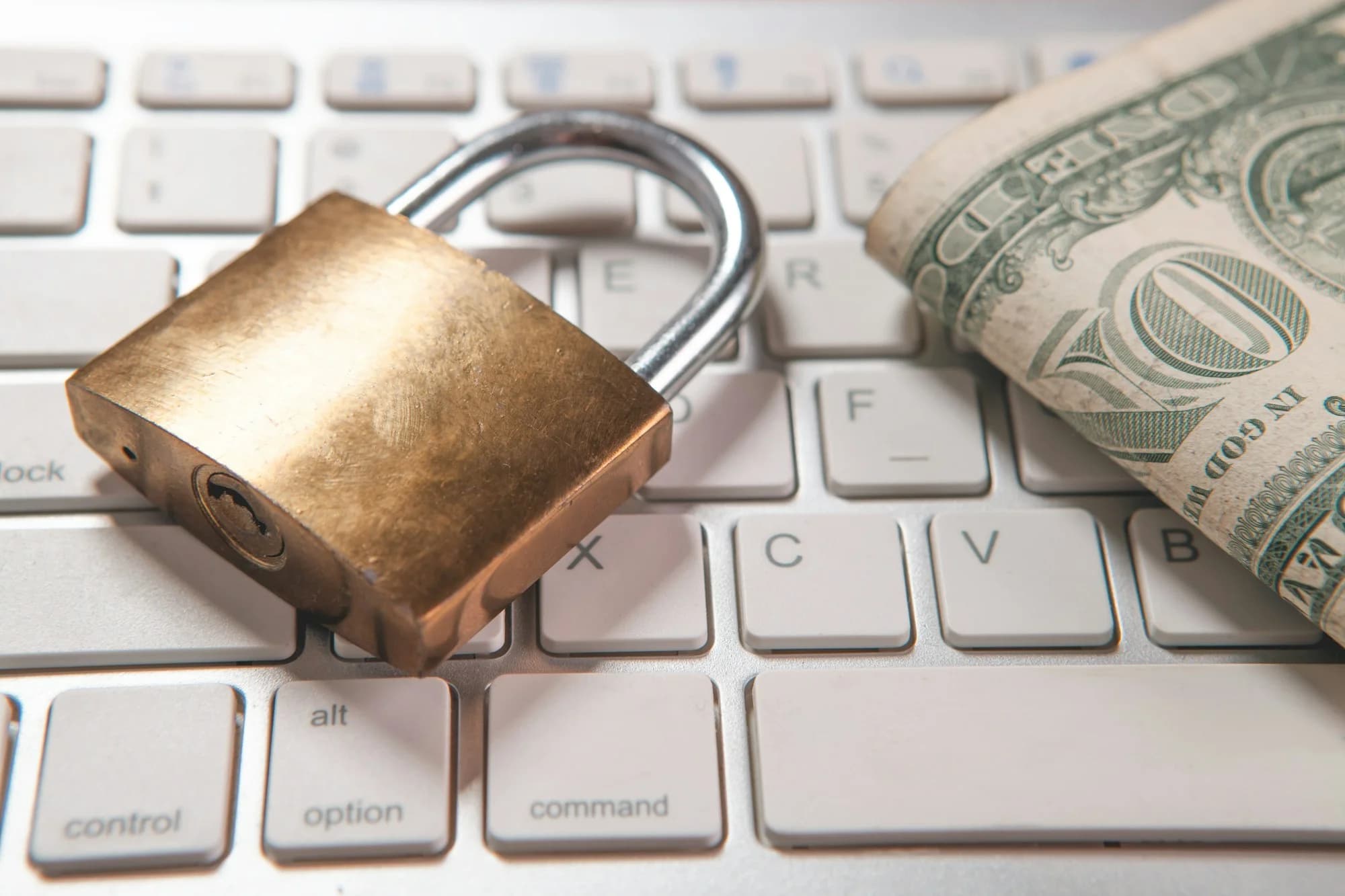 Padlock and dollar bills on a computer keyboard (Sasun Bughdaryan, Unsplash)