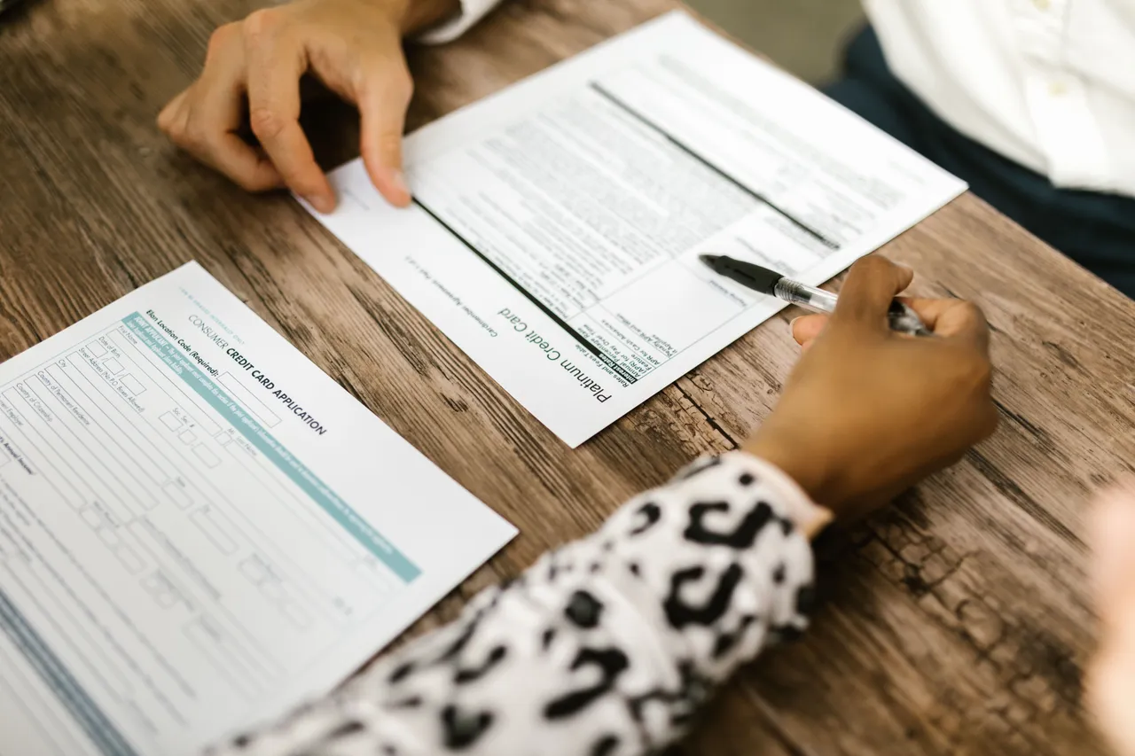 A person writing on a credit card application on white paper