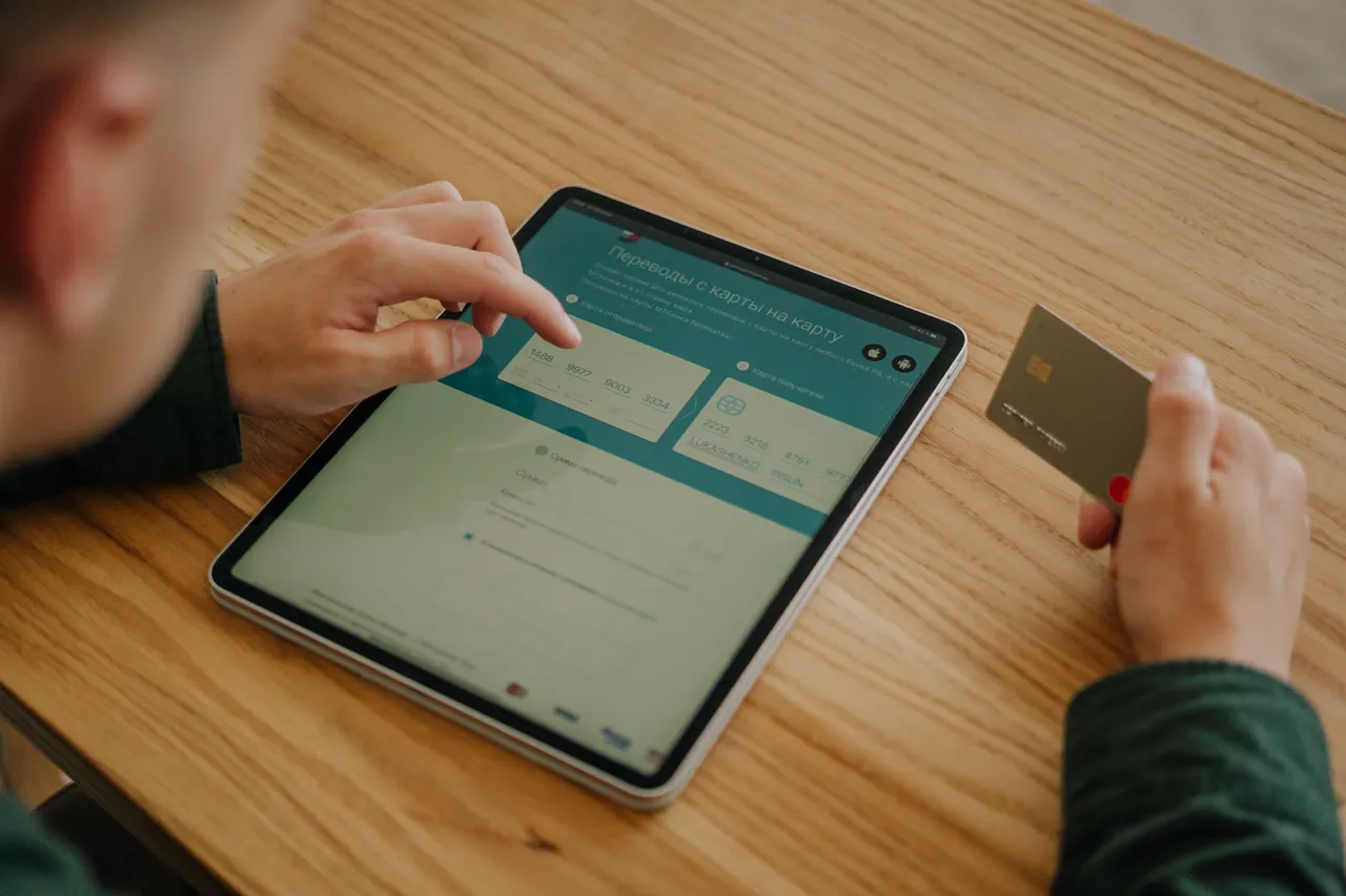 A person using an iPad while holding a credit card
